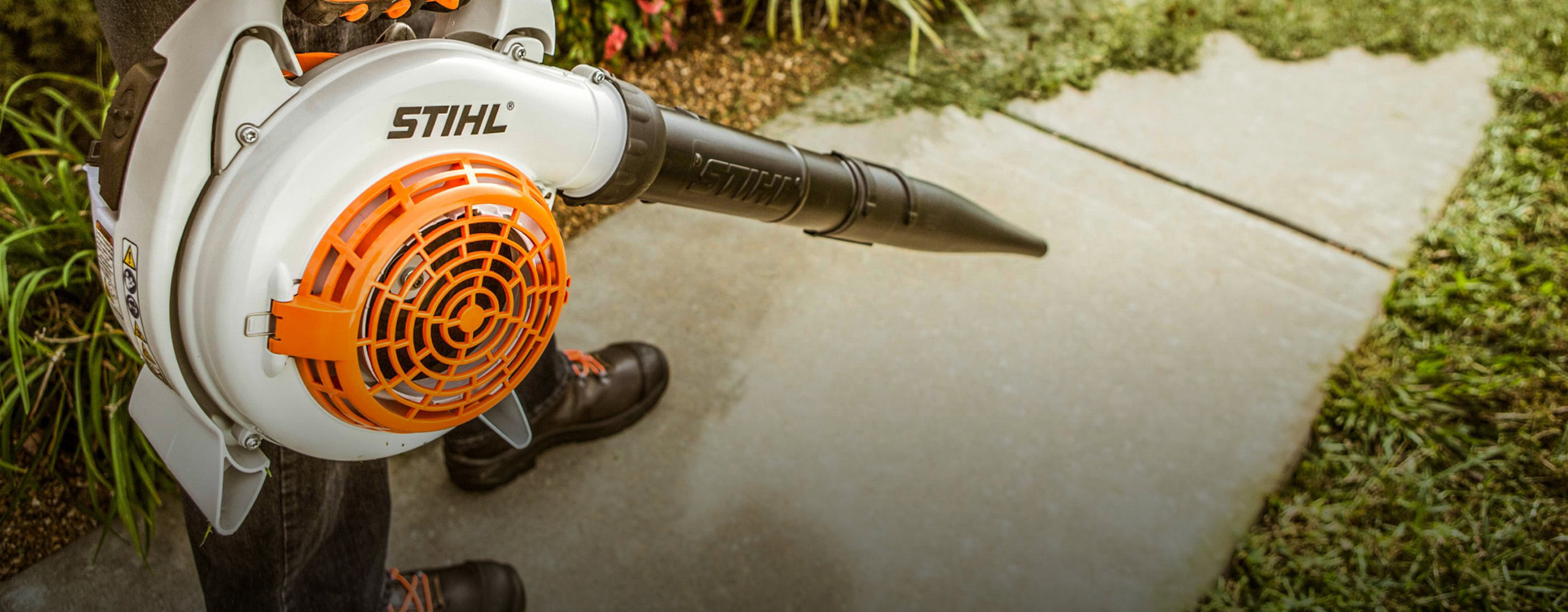 STIHL cordless leaf blower being used for yard cleanup.